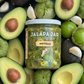 Jar of Jalapa Jar Avocillo surrounded by avocados, tomatillos, and limes.